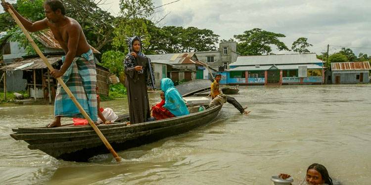 People ride on boat in flooded area.